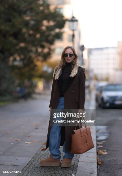 Sonia Lyson wearing Tods Iconic Di brown leather big bag, Tods round brown shades, Ugg plateau chestnut Ultra Mini Platform boots, H&M blue wide leg...