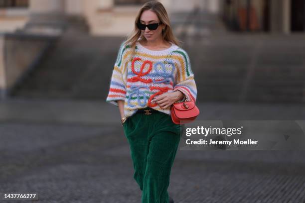 Sonia Lyson wearing Crocs black shoes, Isabel Marant green cord pants, Gucci orange Bamboo leather bag, Loewe colorful striped knit sweater, Celine...