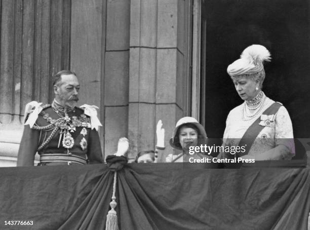 The future Queen Elizabeth II waving from the balcony of Buckingham Palace in London, with her younger sister Margaret and her grandparents King...