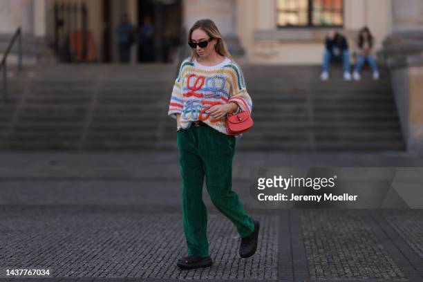 Sonia Lyson wearing Crocs black shoes, Isabel Marant green cord pants, Gucci orange Bamboo leather bag, Loewe colorful striped knit sweater, Celine...