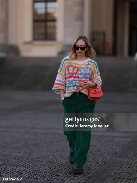 Sonia Lyson wearing Crocs black shoes, Isabel Marant green cord pants, Gucci orange Bamboo leather bag, Loewe colorful striped knit sweater, Celine...