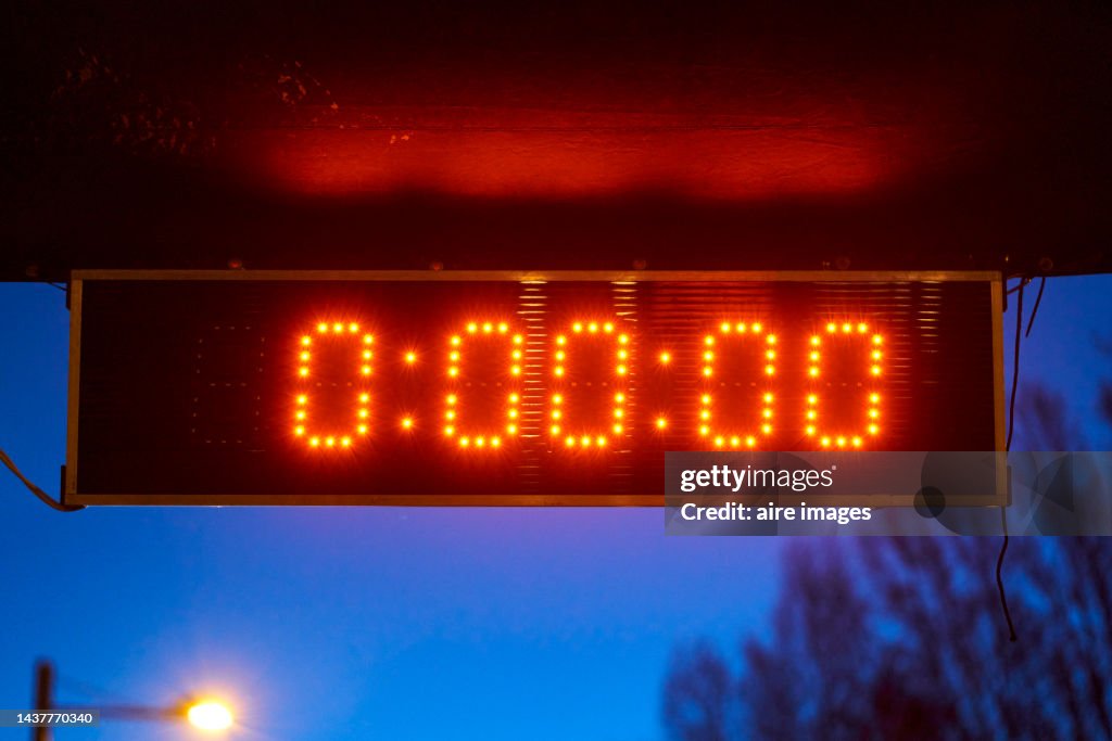 Digital meter marking zero in red numbers in the background you can see that it is getting dark and a pole lighting up