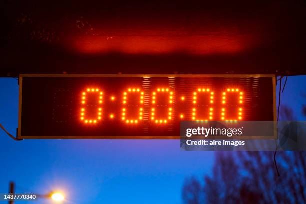 digital meter marking zero in red numbers in the background you can see that it is getting dark and a pole lighting up - count down stock pictures, royalty-free photos & images