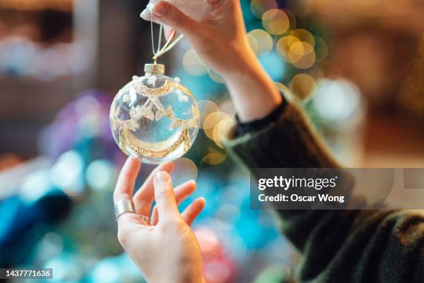 female hands holding a beautiful christmas bauble with defocused lights in the background. - stämningsfull bildbanksfoton och bilder