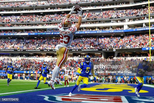 Christian McCaffrey of the San Francisco 49ers catches the ball for a touchdown as Jalen Ramsey and Taylor Rapp of the Los Angeles Rams defend during...