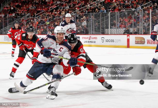 Boone Jenner of the Columbus Blue Jackets skates against John Marino of the New Jersey Devils at the Prudential Center on October 30, 2022 in Newark,...