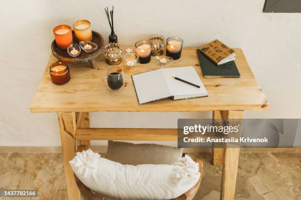 burning candle in glass jar and empty notebook on wooden table. - ceremonia fotografías e imágenes de stock