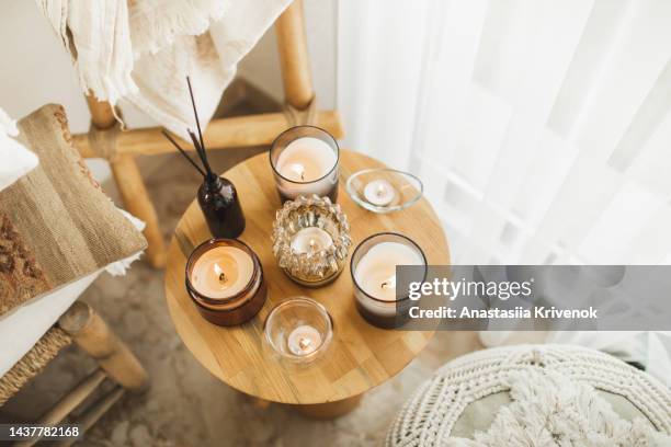 home decoration with burning candles on wooden coffee table in bright and cozy living room. - house warm heating oil stockfoto's en -beelden