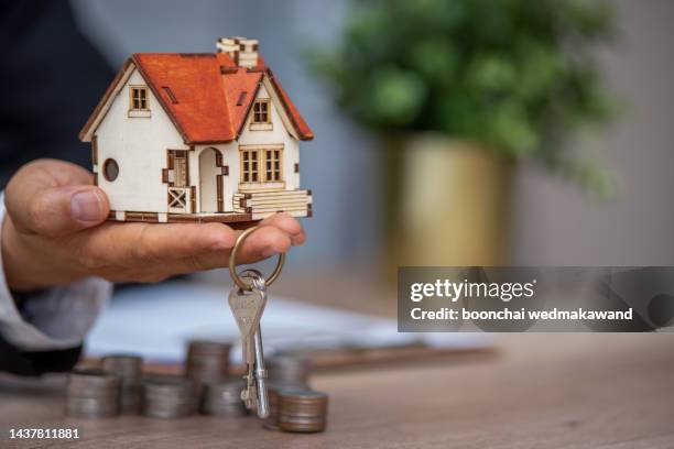 a closeup shot of a person thinking of buying or selling a house - prendere in prestito foto e immagini stock