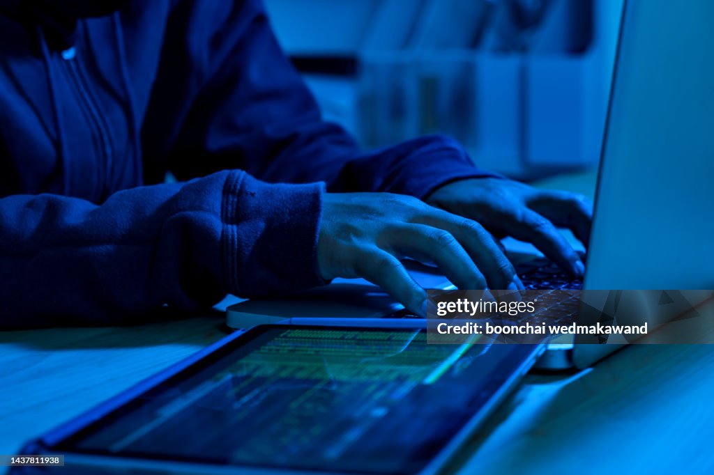Wanted hackers coding virus ransomware using laptops and computers. Cyber attack, system breaking and malware concept.