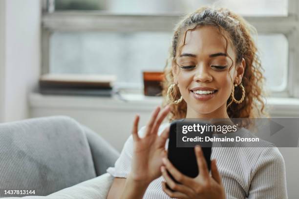 mulher negra com smartphone em um sofá para rede online, aplicativo móvel ou relaxar bate-papo com wi-fi caseiro. jovem no sofá usando telefone para internet, postagem de mídia social ou atualização de comunicação por e-mail - advertisement - fotografias e filmes do acervo