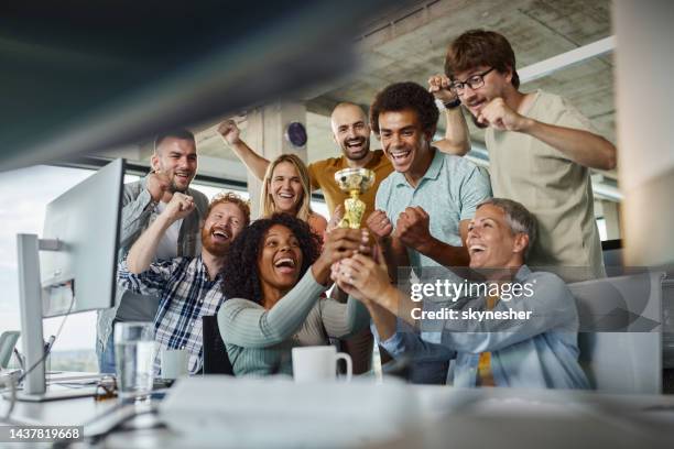 ein team fröhlicher programmierer gewann im büro eine trophäe. - about you awards stock-fotos und bilder