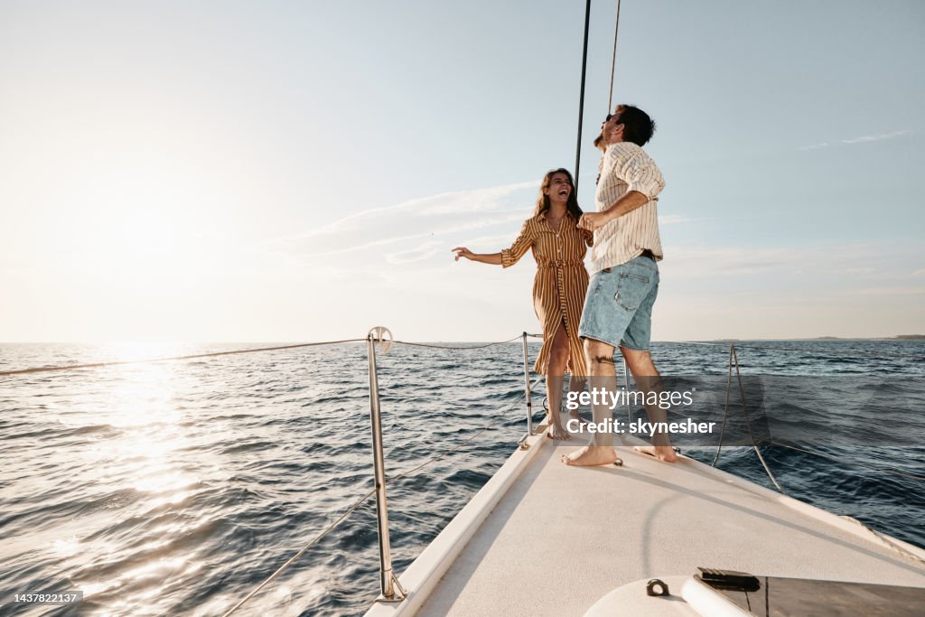 Young carefree couple dancing in summer day on a yacht.