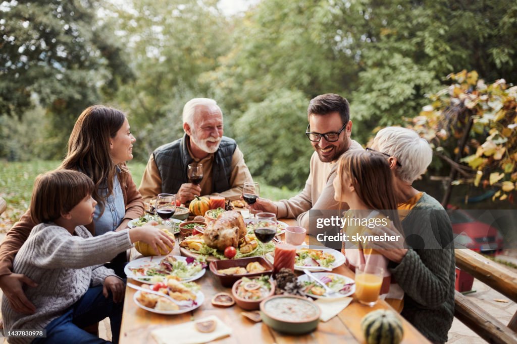 Glückliche Mehrgenerationenfamilie, die das Mittagessen auf einer Terrasse genießt.