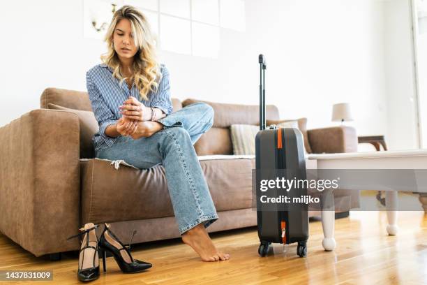young woman sitting on couch in rented apartment - high heels pain stock pictures, royalty-free photos & images