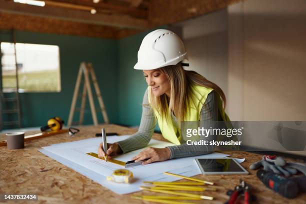 ingeniera sonriente dibujando medidas en el sitio de construcción. - ingeniero civil fotografías e imágenes de stock