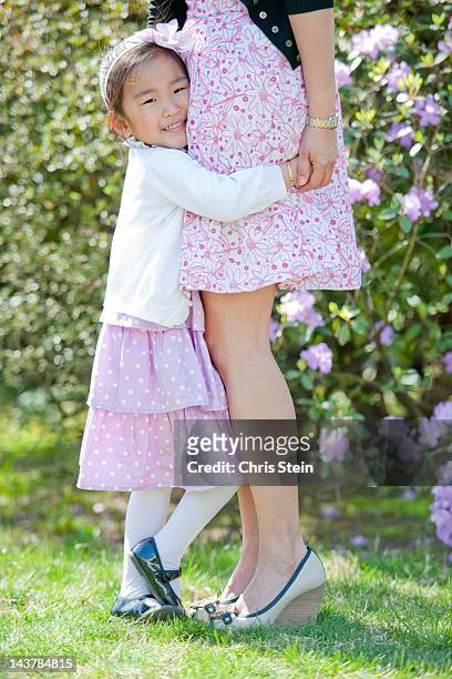 daughter hugging mother's legs - zondagse kleren stockfoto's en -beelden