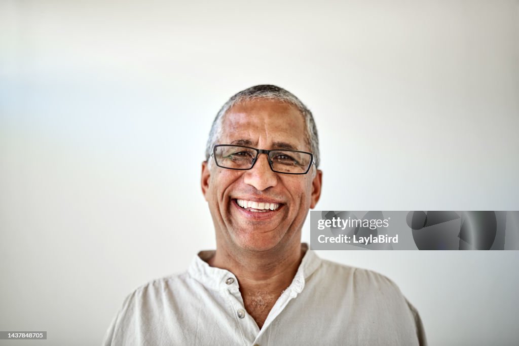 Homem idoso feliz, sorria retrato com fundo de parede branca e relaxe sentado em casa com óculos. Aposentadoria de idosos, velha felicidade e homem negro confiante com rosto orgulhoso, em casa ou asilo