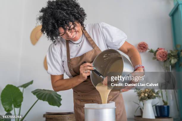 happy mature woman pouring cake mixture into baking tin - bakery apron bildbanksfoton och bilder
