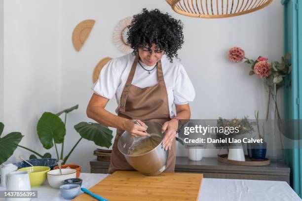 mature beautiful woman mixing cake mixture in her domestic kitchen - fouet photos et images de collection