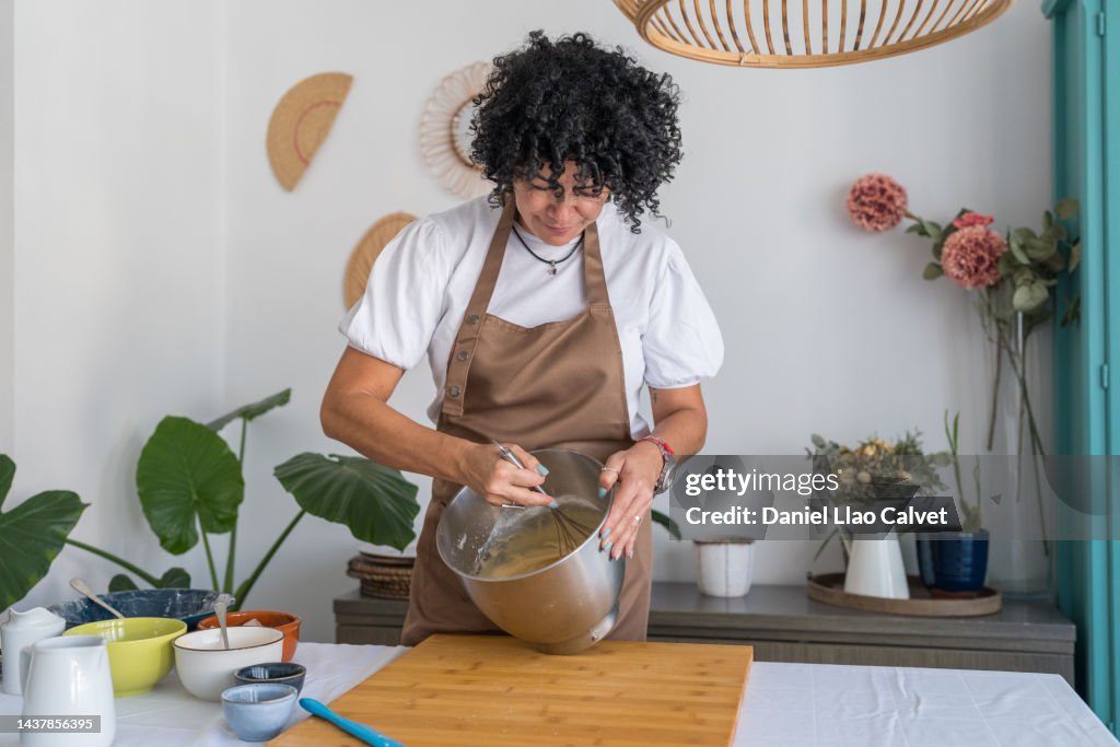 Mature beautiful woman mixing cake mixture in her domestic kitchen