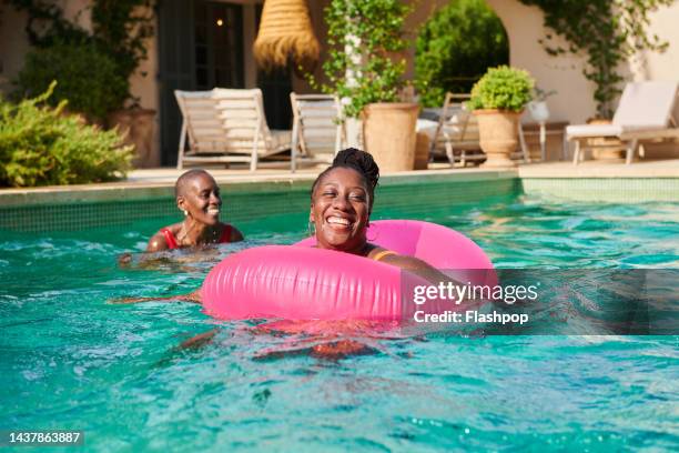 two women smiling in a swimming pool - woman pool relax stockfoto's en -beelden