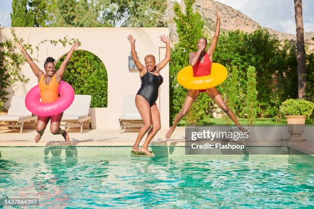 a small group of women jumping into a villa swimming pool - pool party ストックフォトと画像