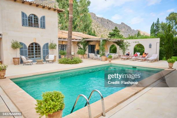 luxury holiday villa. three women lying on sun loungers. - ferienhaus stock-fotos und bilder