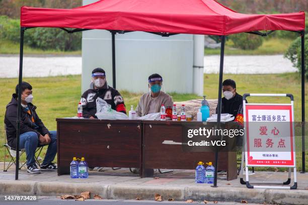 Staff members work at a service point to provide water and food for Foxconn employees before their departure on October 30, 2022 in Zhengzhou, Henan...