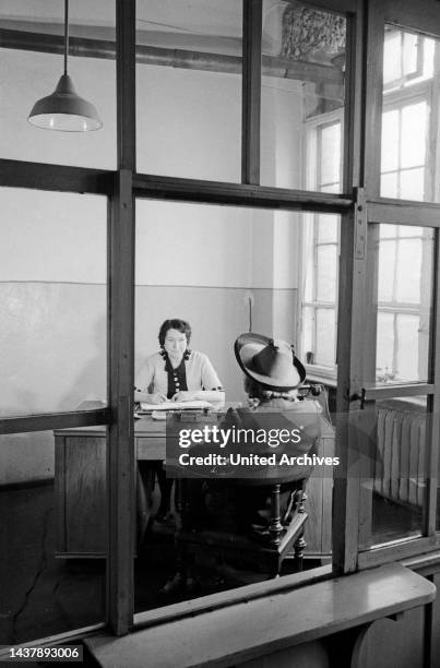 Gespräch zweier Frauen in einem Büro der Mützenfabrik Wolfgang Schmidt in der Greifswalder Strasse 220 in Berlin, Deutschland 1947.