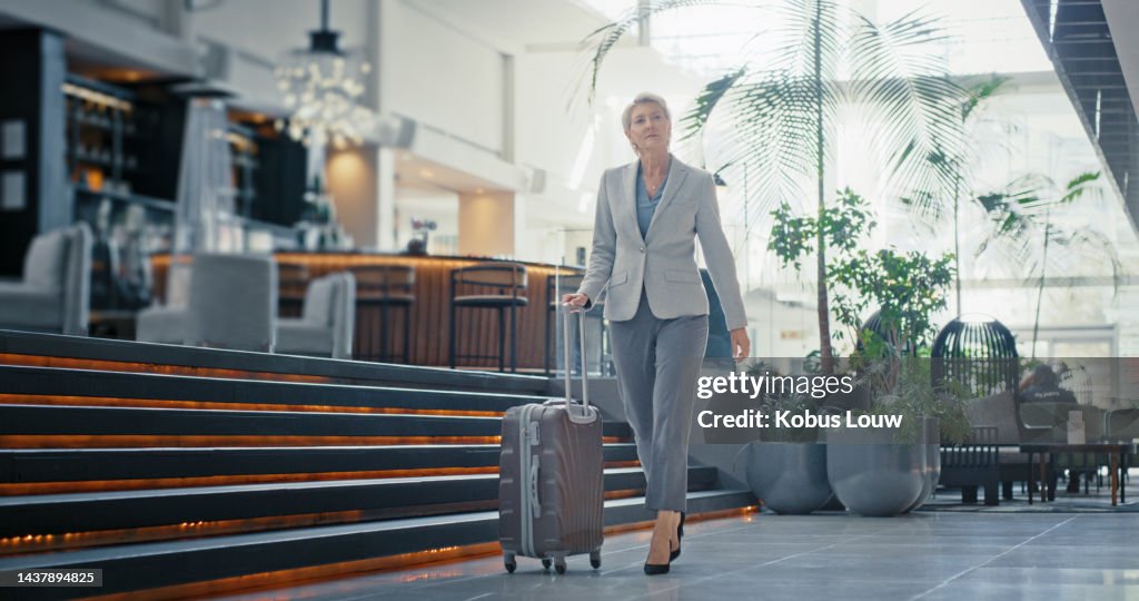 Maleta, viaje y paseo de mujer de negocios en el vestíbulo de recepción del hotel, salón de clase ejecutiva del aeropuerto o moderno edificio de oficinas. Equipaje de viaje, gerente corporativo o liderazgo CEO con mentalidad de éxito