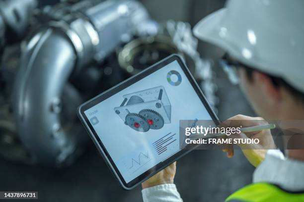 closeup of male engineer contemplating and designing engine by looking at the design model from the tablet, the parts are probably automotive. - aircraft assembly plant fotografías e imágenes de stock