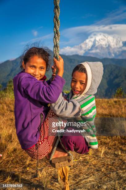 children swinging in village near pokhara, himalayas on background, nepal - nepal girl stock pictures, royalty-free photos & images