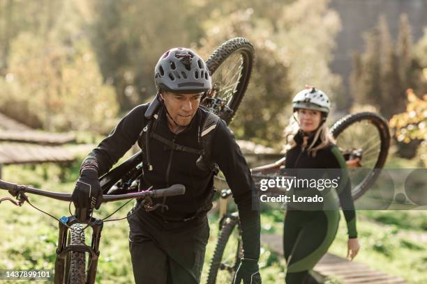 una coppia di mountain biker di razza mista che si prepara per un'avventura - andare in mountain bike foto e immagini stock