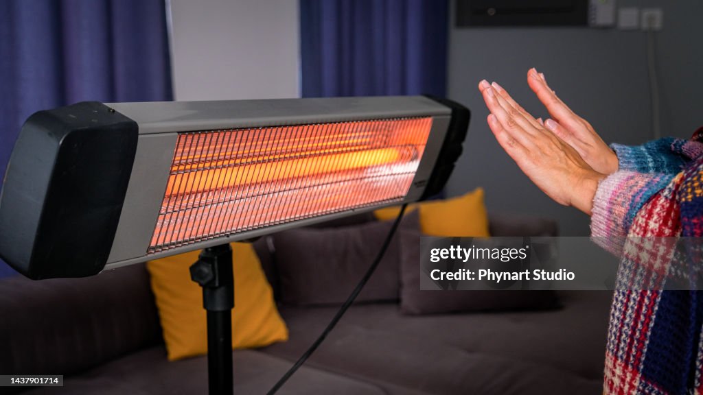 Heat Out Hand Person Heating Their Hands At Home Over A Portable Electric Halogen ...
