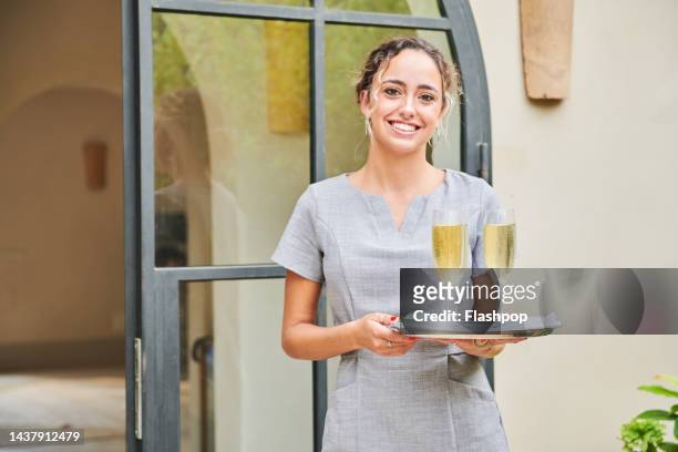 hostess holding a silver tray with welcoming drinks in anticipation of her clients arrival. - hotel concierge stock pictures, royalty-free photos & images
