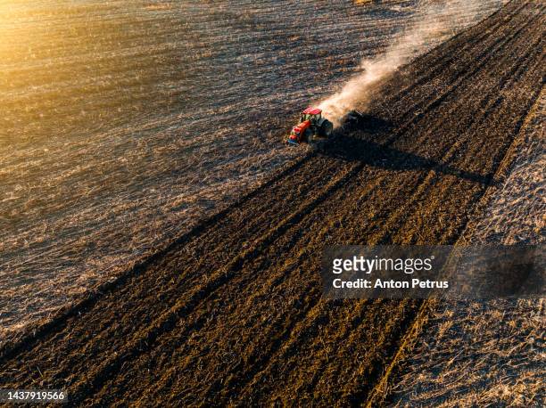 aerial view of a tractor plowing a field at sunset. preparing the field for sowing - ploughed field stock pictures, royalty-free photos & images
