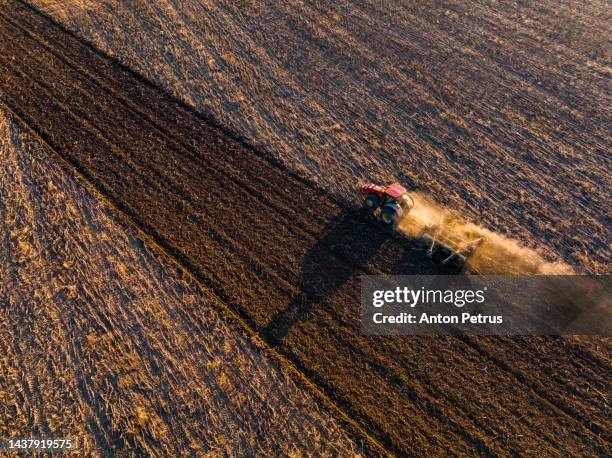 aerial view of a tractor plowing a field at sunset. - ploughed field stock pictures, royalty-free photos & images