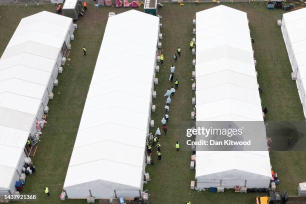 People believed to be migrants are moved between tents at a migrant holding facility at Manston Airfield on October 31, 2022 in Ramsgate, England....