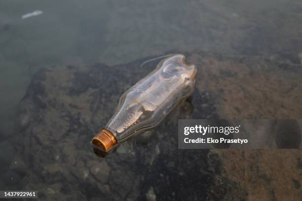 bottled trash floating on the surface of the water - eko atlantic beach stock pictures, royalty-free photos & images
