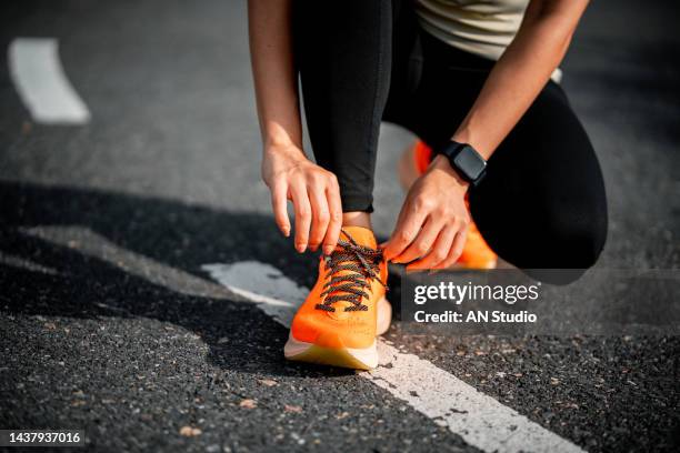 running shoes. woman tying shoe laces. closeup of female sport fitness runner getting ready for jogging outdoors on forest path in late summer or fall. jogging girl exercise motivation heatlh and fitness. - marathon start stock pictures, royalty-free photos & images