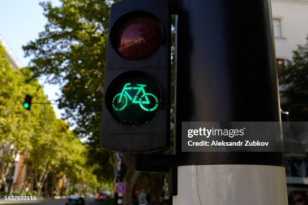 close-up of a green traffic light for bicycles on a bike path next to a road in the city center, on a sunny day. city life. compliance with traffic rules. safety precautions. a traffic light signal that permits the movement of vehicles. - road signal ストックフォトと画像