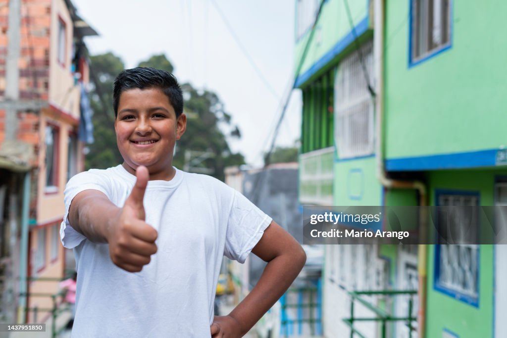 Latin boy with an average age of 13 years old is on the street looking at the camera that portrays him while smiling