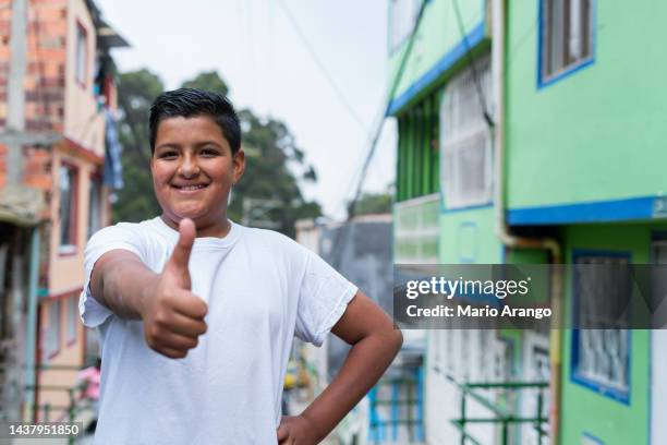 latin boy with an average age of 13 years old is on the street looking at the camera that portrays him while smiling - south american culture stock pictures, royalty-free photos & images