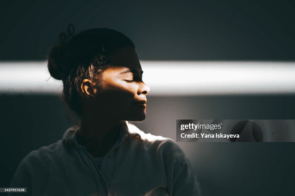Beautiful woman portrait against the sun ray, light and shadow play