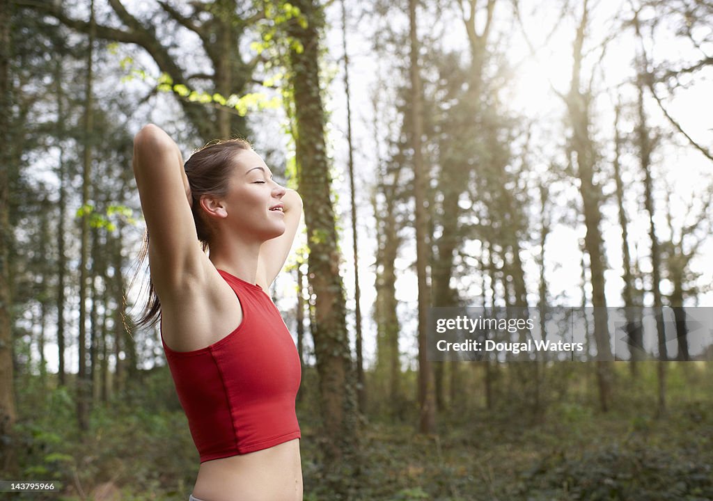 Female runner in woodland with eyes closed.