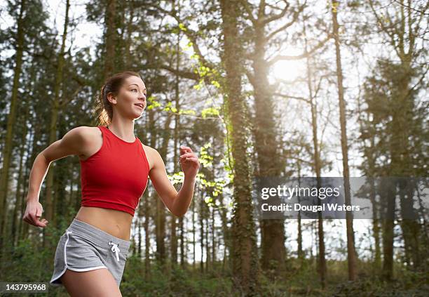 woman running in woodland. - running shorts stock pictures, royalty-free photos & images