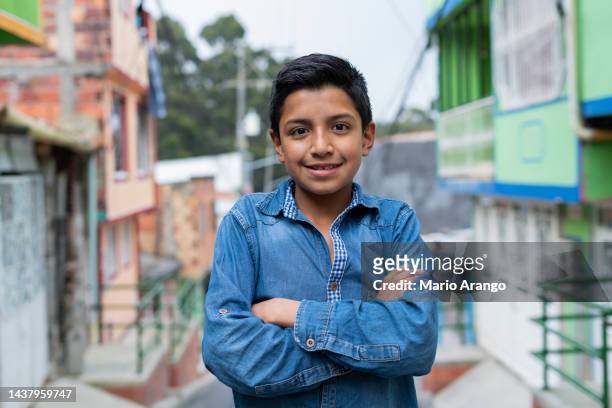 latin boy mit einem durchschnittsalter von 10 jahren ist auf der straße und schaut in die kamera, die ihn porträtiert, während er lächelt - girl 10 years old happy stock-fotos und bilder
