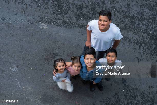 latino brothers are on the street of the neighborhood where they live looking towards the camera that portrays them - zuid amerikaanse cultuur stockfoto's en -beelden