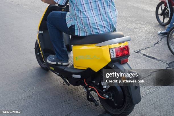 detail of thai man on electric motorcycle. - lambreta imagens e fotografias de stock